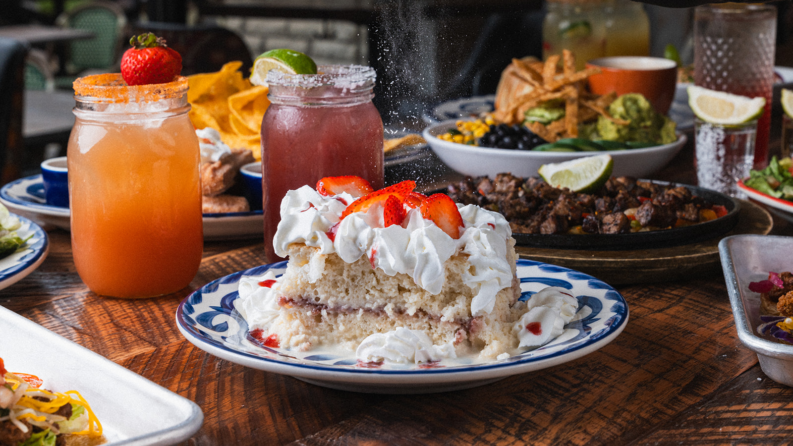 Strawberry and citrus cocktails on a wooden table alongside shared plates at Social Cantina in downtown Nashville
