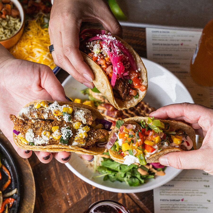 Two people picking up street tacos from a shared plate at Social Cantina in downtown Nashville