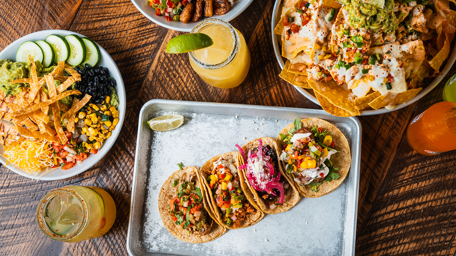 A tray of four tacos beside a cantina bowl and nachos at Social Cantina in downtown Nashville