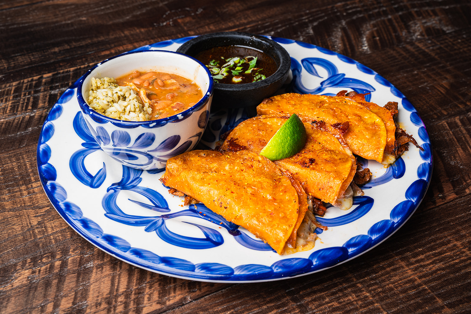 Quesabirria tacos with a side of consomme on a hand-painted plate at Social Cantina Nashville