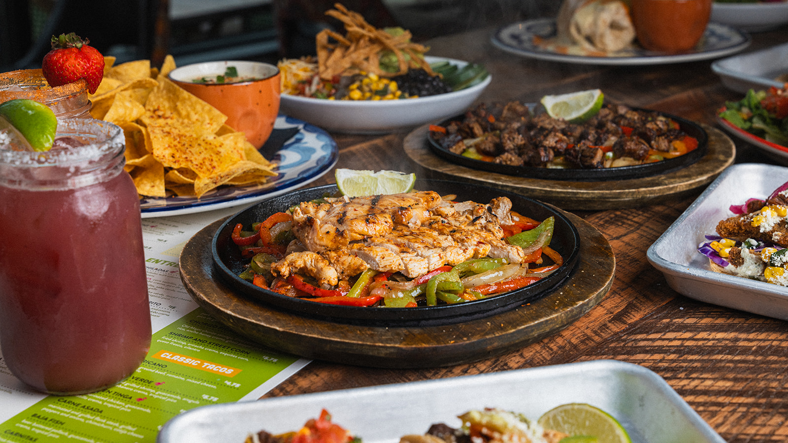 Chicken and steak fajitas, chips and queso, and a strawberry margarita on a table at Social Cantina Nashville